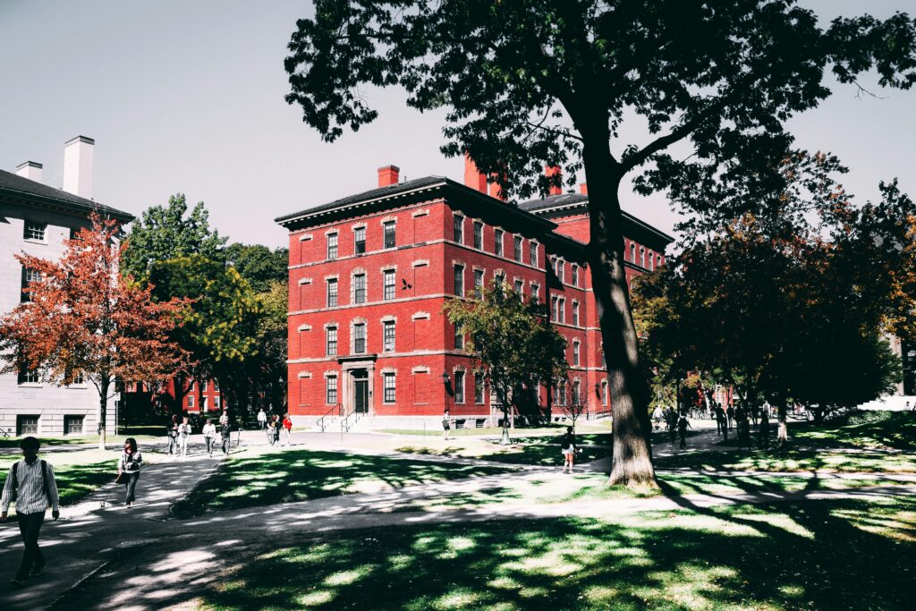 View of a historic red brick university building surrounded by lush trees and walking paths.