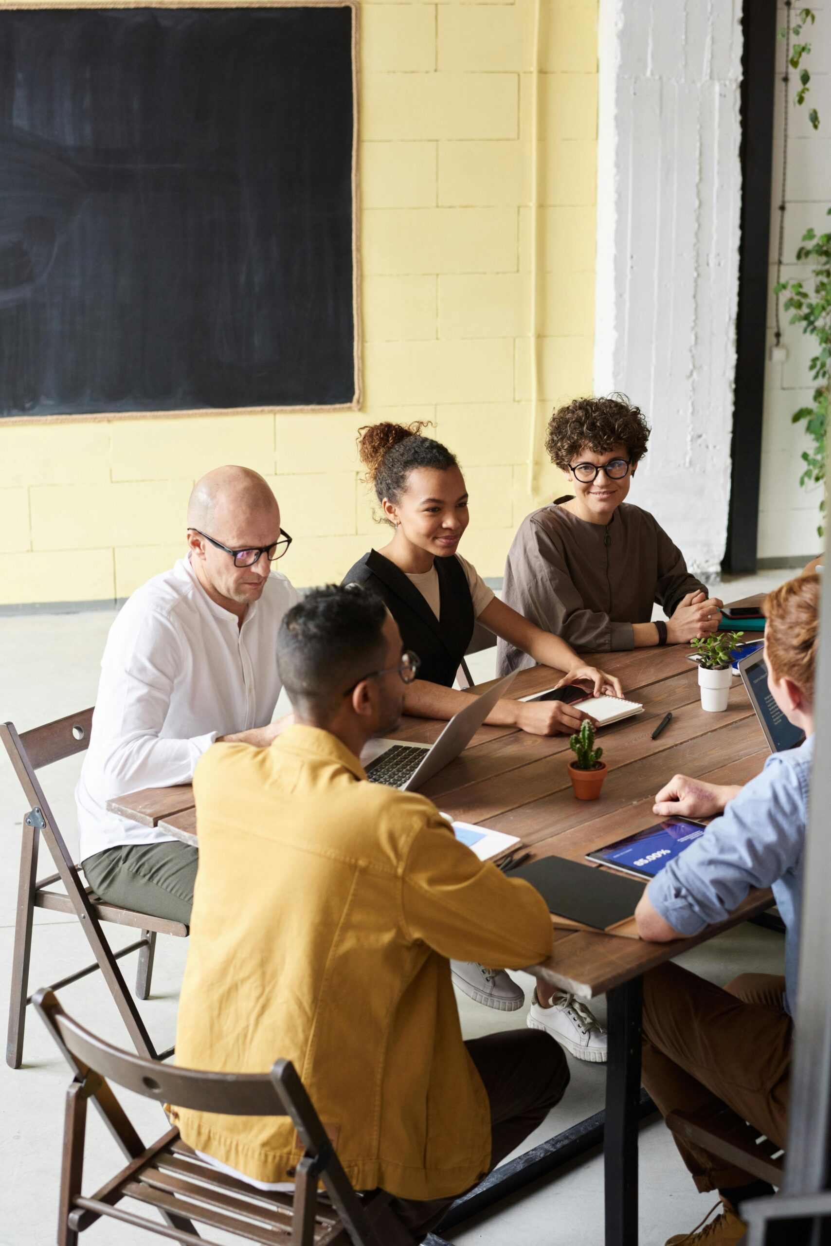 A diverse group of professionals engaging in a collaborative meeting around a wooden table in a modern office setting.