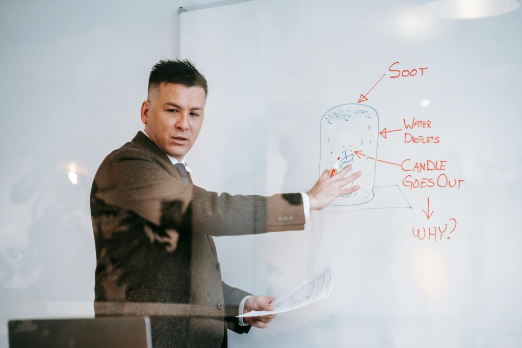 Professional man explaining a science concept on a whiteboard during a teaching session.