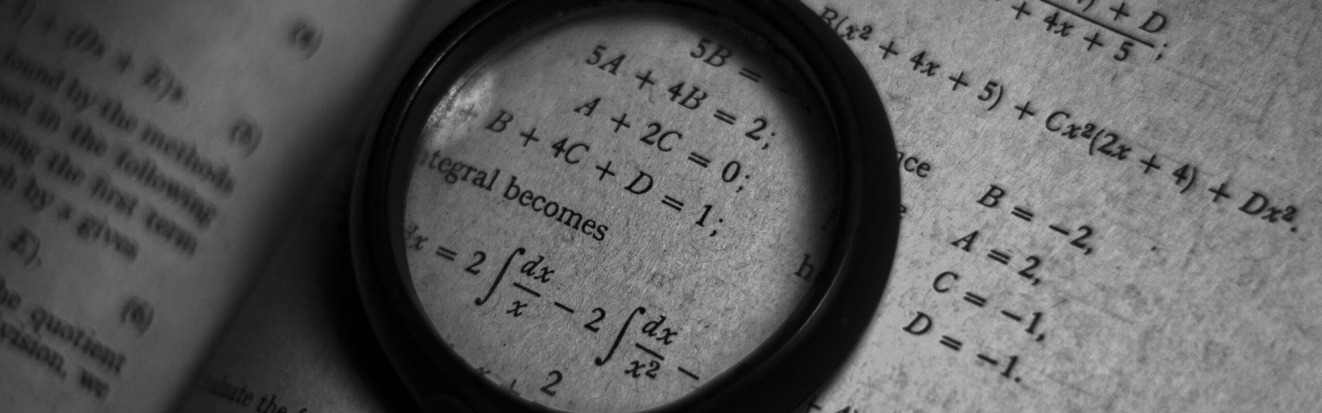 A magnifying glass focuses on mathematics formulas in a book, enhancing study and exploration.